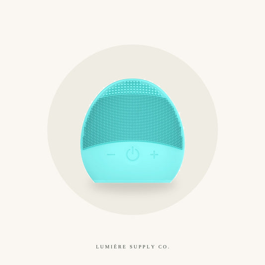 Silicone cleansing brush in mint, on a cream background